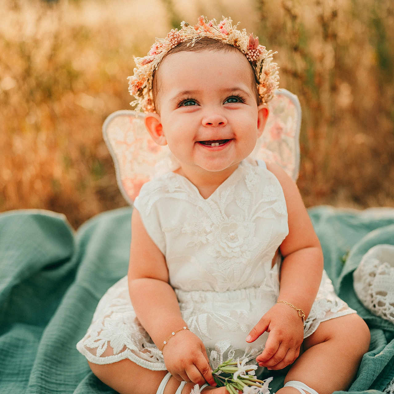 Millie joined the competition — help win amazing prizes! baby, bracelet, child, cute, flower, flower_crown, grass, green_blanket, happy, headband, infant, lace, nature, outdoor, portrait, sitting, smiling, sunlight, toes, white_dress