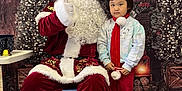 Cing is registered to the contest to win money with this photo: child, santa_claus, christmas, holiday, festive, red_clothing, white_beard, glasses, scarf, candy_cane, indoor, decorations, tree, smile, boots, floor, chair, table, gift_box, portrait
