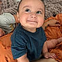 Jesse James is registered to the contest to win money with this photo: arm, baby, blanket, blue_shirt, candid, child, comfort, cute, face, hand, happy, indoors, infant, knit_blanket, orange_blanket, person, portrait, resting, smile, tattoo