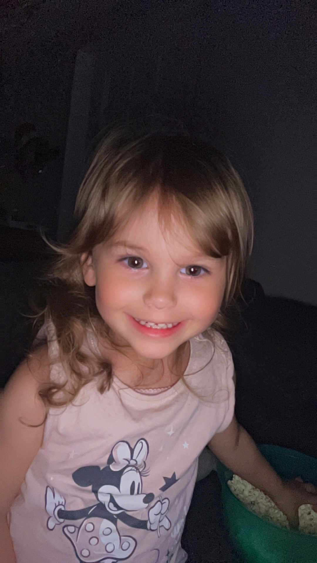 Athena participe au concours pour gagner de l'argent avec cette photo : child, smiling, popcorn, indoor, tshirt, minnie_mouse, young_child, happy, person, cute, girl, snack, food, light_brown_hair, casual_clothing, portrait, face, hand, dark_background, cozy