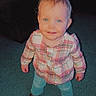 toddler, child, blue_eyes, plaid_shirt, jeans, brown_shoes, carpet, indoor, standing, smiling, person, cute, young_child, blond_hair, toy, blanket, home, portrait, happy, casual_clothing