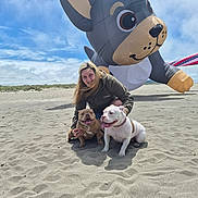 Chica And Tony is registered to the contest to win money with this photo: woman, dog, bulldog, beach, sand, inflatable, balloon, sky, cloud, smile, outdoor, pet, animal, happy, playful, casual_clothing, fun, daytime, recreation, nature