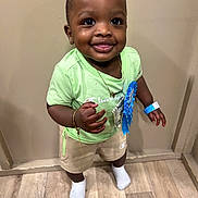 Nymari joined the competition — help win amazing prizes! toddler, child, smiling, standing, indoor, green_shirt, shorts, blue_ribbon, bracelet, necklace, socks, flooring, wood_floor, face, happy, cute, person, portrait, young_child, champion