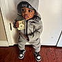 child, toddler, hoodie, nike, sneakers, money, indoor, wood_floor, headband, casual_clothing, standing, person, young_child, fashion, cute, expression, black_hair, face, real_photo, hooded_jacket