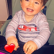 Nael participe au concours pour gagner de l'argent avec cette photo : cheerful, child, clothing, cute, expression, face, fire_truck, hair, hands, happy, high_chair, indoor, long_sleeve, pink, red, skin, smile, table, toddler, toy