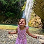 Romy participe au concours pour gagner de l'argent avec cette photo : child, girl, waterfall, nature, rocks, river, outdoor, smiling, dress, pink, trees, sunlight, happy, playful, summer, water, forest, scenic, adventure, portrait