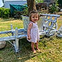 barefoot, child, cute, daytime, dress, flower_pot, garden, grass, greenery, nature, outdoor, plants, standing, summer, sunlight, toddler, tree, wheelbarrow, wooden, yard