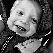 Lyam participe au concours pour gagner de l'argent avec cette photo : child, toddler, smile, face, teeth, jacket, hood, black_and_white, closeup, happy, eyes, cozy, fabric, baby, portrait, cute, warm, young_child, seatbelt, car_seat
