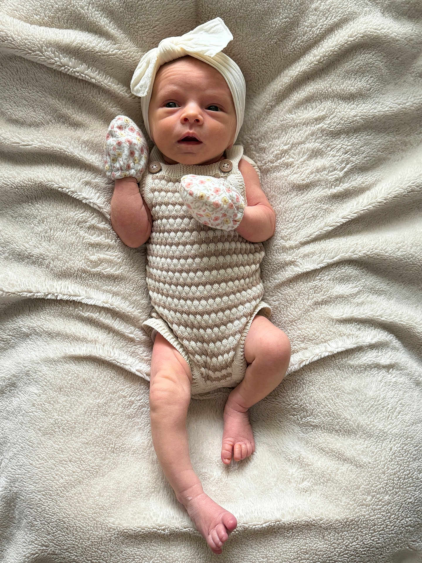 Willow is registered to the contest to win money with this photo: baby, newborn, infant, blanket, headband, mittens, knitted, romper, lying_down, soft_texture, cute, small_feet, small_hands, portrait, indoors, cozy, sleepwear, neutral_colors, closeup, child