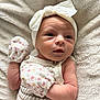 Willow is registered to the contest to win money with this photo: baby, newborn, infant, mittens, headband, bow, knitted_outfit, blanket, soft_texture, cute, portrait, sleepwear, child, small, pink, floral_pattern, lying_down, close_up, skin, peaceful