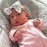 Rebecca is registered to the contest to win money with this photo: baby, infant, onesie, headband, bow, face, hands, cushion, pattern, animal_print, pink, soft_texture, indoor, portrait, newborn, cute, child, cozy, comfortable, clothing