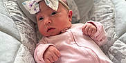 Rebecca is registered to the contest to win money with this photo: baby, infant, onesie, headband, bow, face, hands, cushion, pattern, animal_print, pink, soft_texture, indoor, portrait, newborn, cute, child, cozy, comfortable, clothing