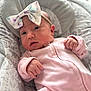 baby, infant, onesie, headband, bow, face, hands, cushion, pattern, animal_print, pink, soft_texture, indoor, portrait, newborn, cute, child, cozy, comfortable, clothing