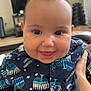 Rebecca is registered to the contest to win money with this photo: baby, child, smiling, indoor, face, person, clothing, pattern, hanukkah, menorah, celebration, happy, cute, portrait, hand, furniture, television, home, buttoned_shirt, infant