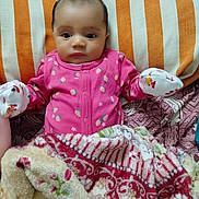 Kiana a rejoint le concours — aidez-le/la à gagner de superbes lots ! baby, infant, pink_onesie, mittens, blanket, striped_pillow, bed, patterned_blanket, face, person, cute, indoors, resting, sleepwear, young_child, cozy, portrait, lying_down, small_hands, curious_expression