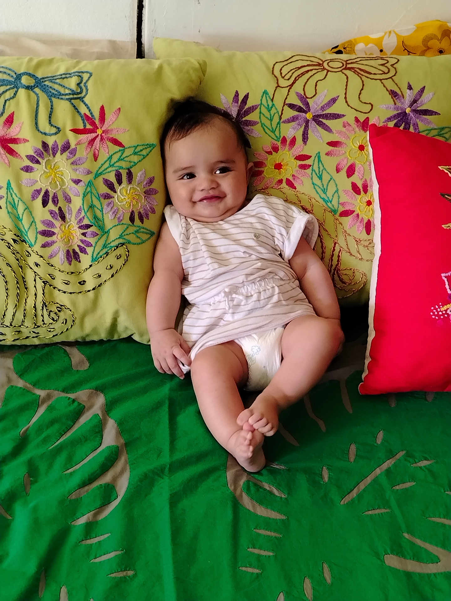 Kiana a rejoint le concours — aidez-le/la à gagner de superbes lots ! baby, child, smile, couch, pillow, embroidery, colorful, striped_clothing, diaper, indoor, happy, infant, person, sitting, green, red, fabric, cozy, cute, portrait