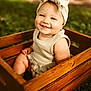 Aryanna is registered to the contest to win money with this photo: baby, child, smile, headband, bow, wooden_crate, outdoor, grass, greenery, portrait, cute, happy, toddler, infant, nature, sunlight, clothing, person, sitting, photography