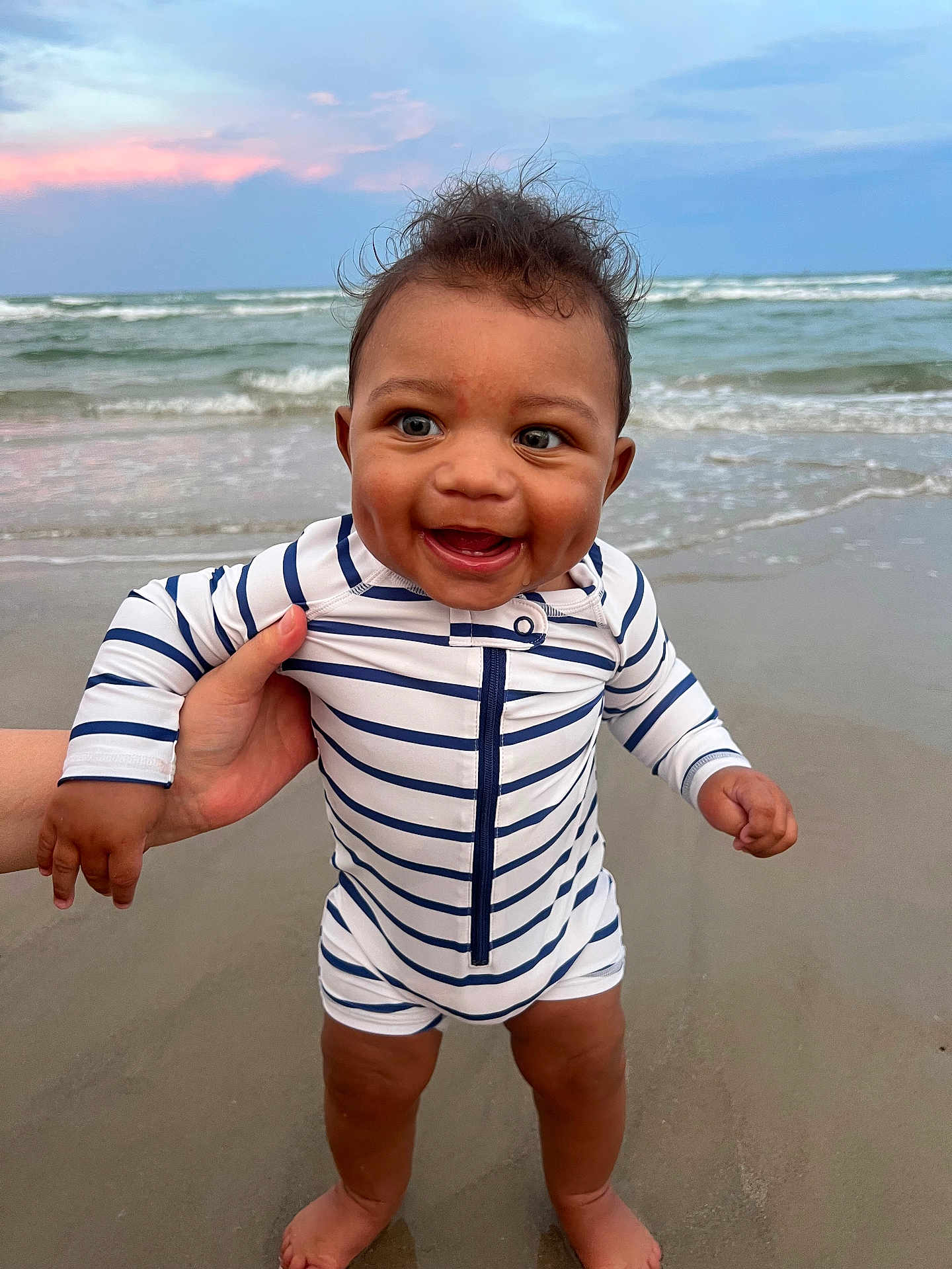 Amereond joined the competition — help win amazing prizes! baby, child, beach, ocean, water, waves, sunset, sky, sand, striped_clothing, smiling, happy, person, hand, standing, outdoor, foot, infant, cute, summer