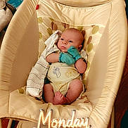 Alex is registered to the contest to win money with this photo: baby, infant, child, portrait, sitting, bouncer, baby_chair, mittens, onesie, blanket, indoor, home, wood_floor, furniture, cozy, face, eyes_open, serious_expression, monday_text, casual_photograph
