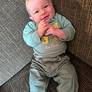 Giovanni participe au concours pour gagner de l'argent avec cette photo : baby, infant, smiling, clothing, green_shirt, pants, socks, couch, fabric, texture, happy, portrait, indoor, person, child, cute, hands, face, seated, cozy