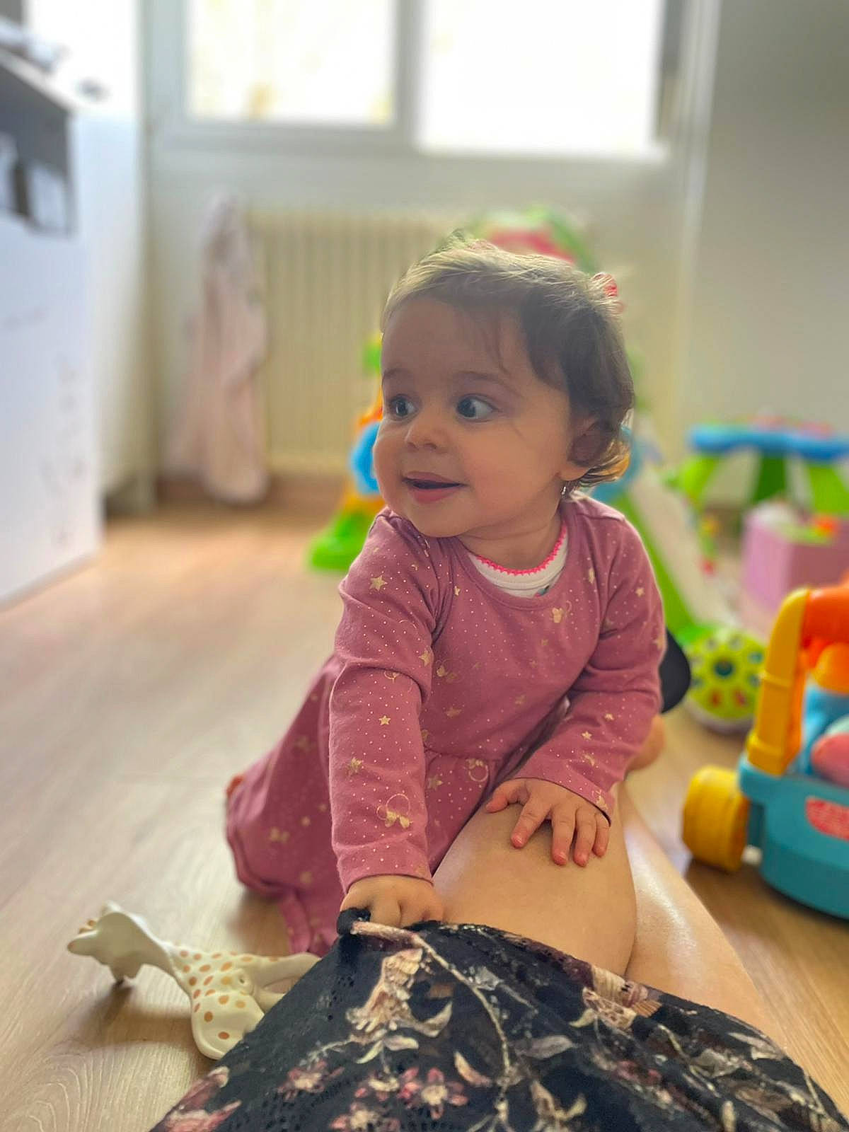 Victoria participe au concours pour gagner de l'argent avec cette photo : baby, baby_playing_with_toys, baby_toddler_clothing, baby_toys, child, floor, flooring, fun, happy, human_leg, person, reptile, room, sitting, skin, smile, standing, toddler, toy, wood