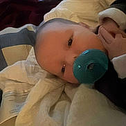 Patrick joined the competition — help win amazing prizes! baby, pacifier, blanket, bed, sleepy, infant, child, cozy, soft, cute, person, indoors, resting, clothing, white, dark, hand, face, lying_down, comfort