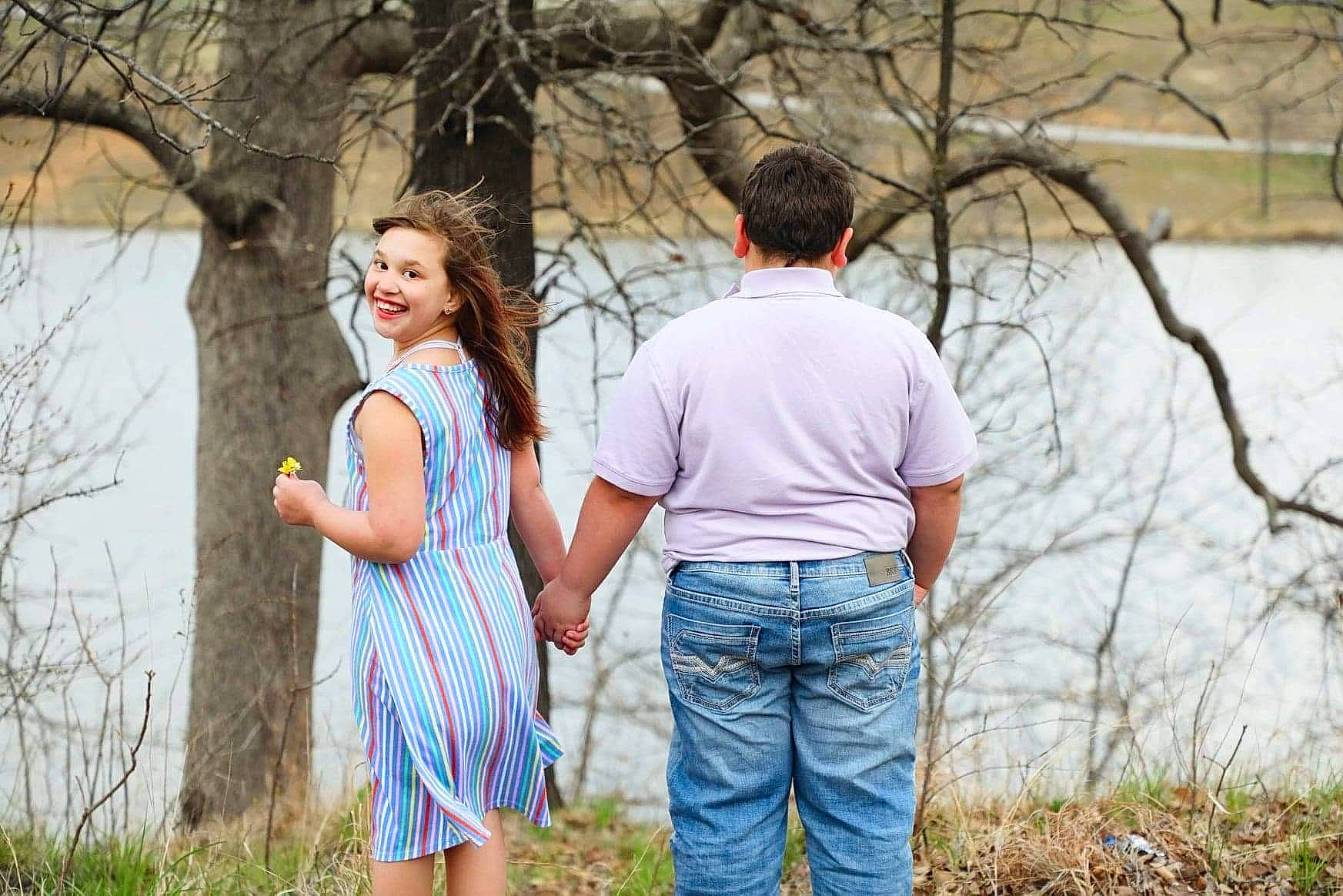 Andrea is registered to the contest to win money with this photo: brown_hair, forest, fun, gesture, grass, happy, holding_hands, joy, landscape, leaf, leisure, natural_landscape, nature, people, people_in_nature, person, plant, recreation, t_shirt, tree