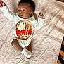 Amir joined the competition — help win amazing prizes! baby, infant, blanket, onesie, socks, face, person, lying_down, bed, baby_clothing, pattern, soft, cute, newborn, indoor, wooden_furniture, curly_hair, skin, sleepwear, resting