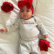 Penelope joined the competition — help win amazing prizes! baby, child, red_bow, headband, striped_clothing, flower, red_flower, bed, white_bedspread, lying_down, infant, cute, portrait, face, hands, soft_lighting, indoor, person, smiling, young_child