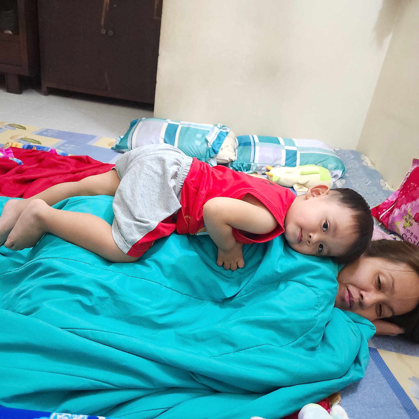 Ryu Le Nguyen joined the competition — help win amazing prizes! bedroom, blanket, casual, child, comfort, cushion, family, floor, gray_shorts, home, indoor, pillow, portrait, red_shirt, relaxation, resting, sleeping, toddler, toy, woman