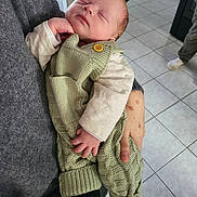 Marceau participe au concours pour gagner de l'argent avec cette photo : baby, sleeping, infant, knitted_clothing, green_outfit, hand, person, indoor, floor_tiles, cozy, cute, peaceful, resting, child, young, portrait, casual, home, holding, relaxed