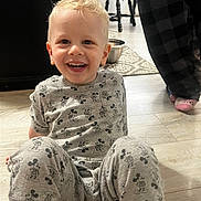 Avryall Apollo is registered to the contest to win money with this photo: toddler, child, smiling, indoor, pajamas, mickey_mouse, floor, wooden_floor, blonde_hair, happy, person, chair, metal_bowl, home, casual_clothing, sitting, feet, patterned_clothing, light, cozy