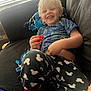 Avryall Apollo joined the competition — help win amazing prizes! child, smiling, blond_hair, pajamas, toy, couch, indoor, window, sunlight, happy, casual_clothing, relaxed, blue_shirt, black_pants, patterned_pants, red_toy, home, person, seated, cozy