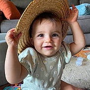 Aurora joined the competition — help win amazing prizes! baby, child, smiling, hat, straw_hat, indoor, living_room, toy, play_mat, cute, happy, infant, person, clothing, sitting, carpet, furniture, couch, colorful, soft_lighting