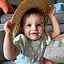 baby, child, smiling, hat, straw_hat, indoor, living_room, toy, play_mat, cute, happy, infant, person, clothing, sitting, carpet, furniture, couch, colorful, soft_lighting