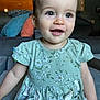Aurora is registered to the contest to win money with this photo: toddler, child, smile, green_dress, floral_pattern, indoor, couch, pillows, home_interior, happy, person, face, cute, sitting, casual_clothing, baby, young_child, bright_eyes, portrait, cozy