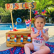Ryder joined the competition — help win amazing prizes! baby, child, popsicles, pool, summer, patriotic, red_white_blue, blanket, outdoor, sunny, headband, clapping, sign, wooden_stand, plants, water, fun, celebration, happy, person