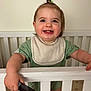 Ryder is registered to the contest to win money with this photo: toddler, child, smile, happy, crib, bib, comb, green_clothing, indoor, baby, portrait, hair_tie, furniture, person, cute, standing, infant, young_child, playful, home