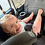 toddler, child, car_seat, smile, happy, hair_tie, baby, seatbelt, car_interior, window, skin, face, person, foot, clothing, seat, safety, cute, infant, playful