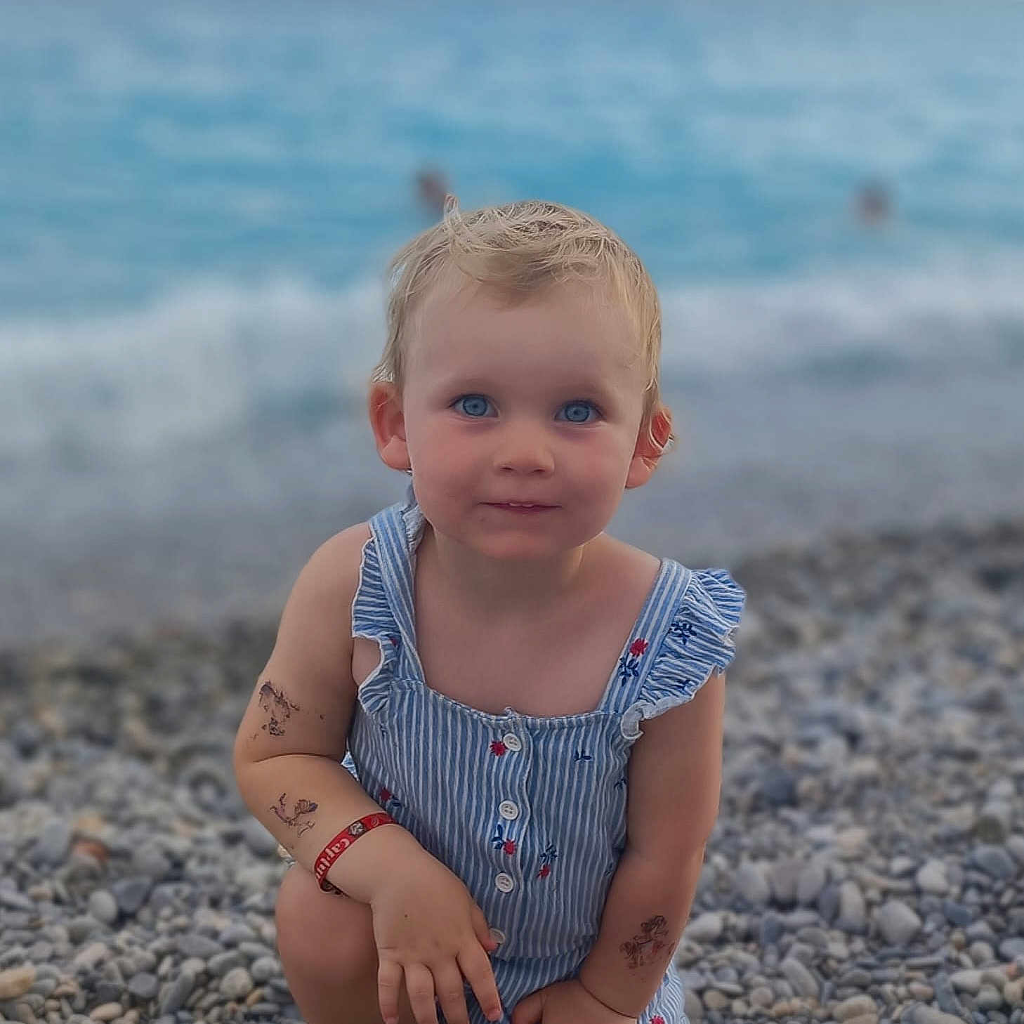 Mila a rejoint le concours — aidez-le/la à gagner de superbes lots ! baby, beach, beachwear, blonde, clothing, coast, face, hair, head, nature, outdoors, pebble, person, photography, portrait, rock, sea, shoreline, sitting, water