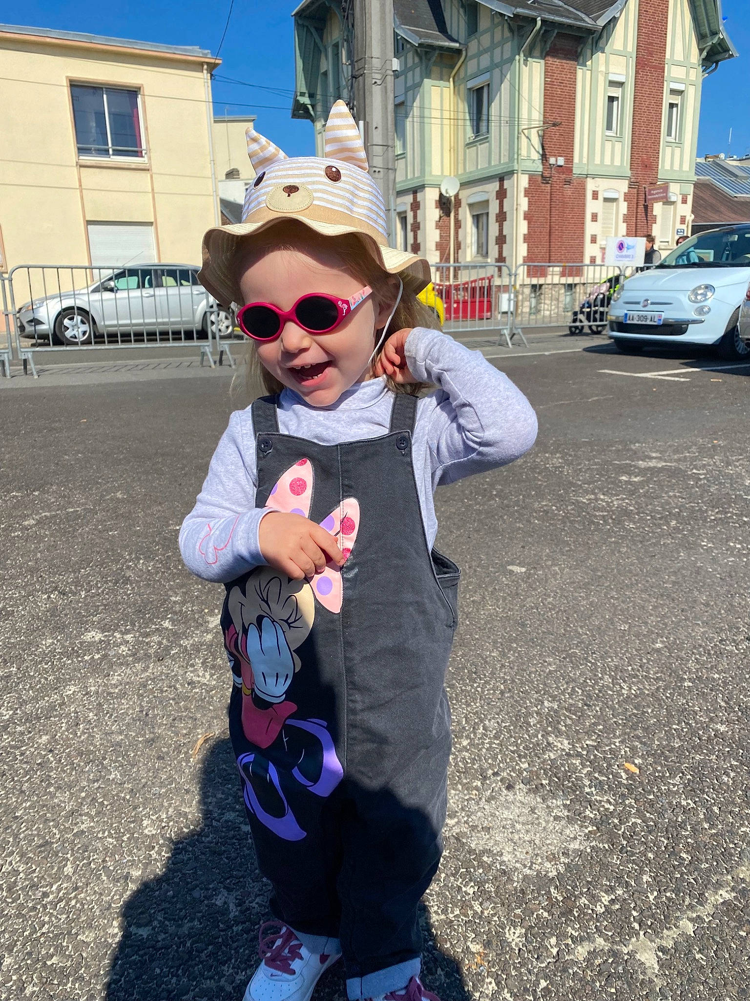 Camille a rejoint le concours — aidez-le/la à gagner de superbes lots ! asphalt, building, car, cool, eyewear, fun, glasses, goggles, hat, person, plant, road_surface, sky, street_fashion, sun_hat, sunglasses, tire, vision_care, wheel, white