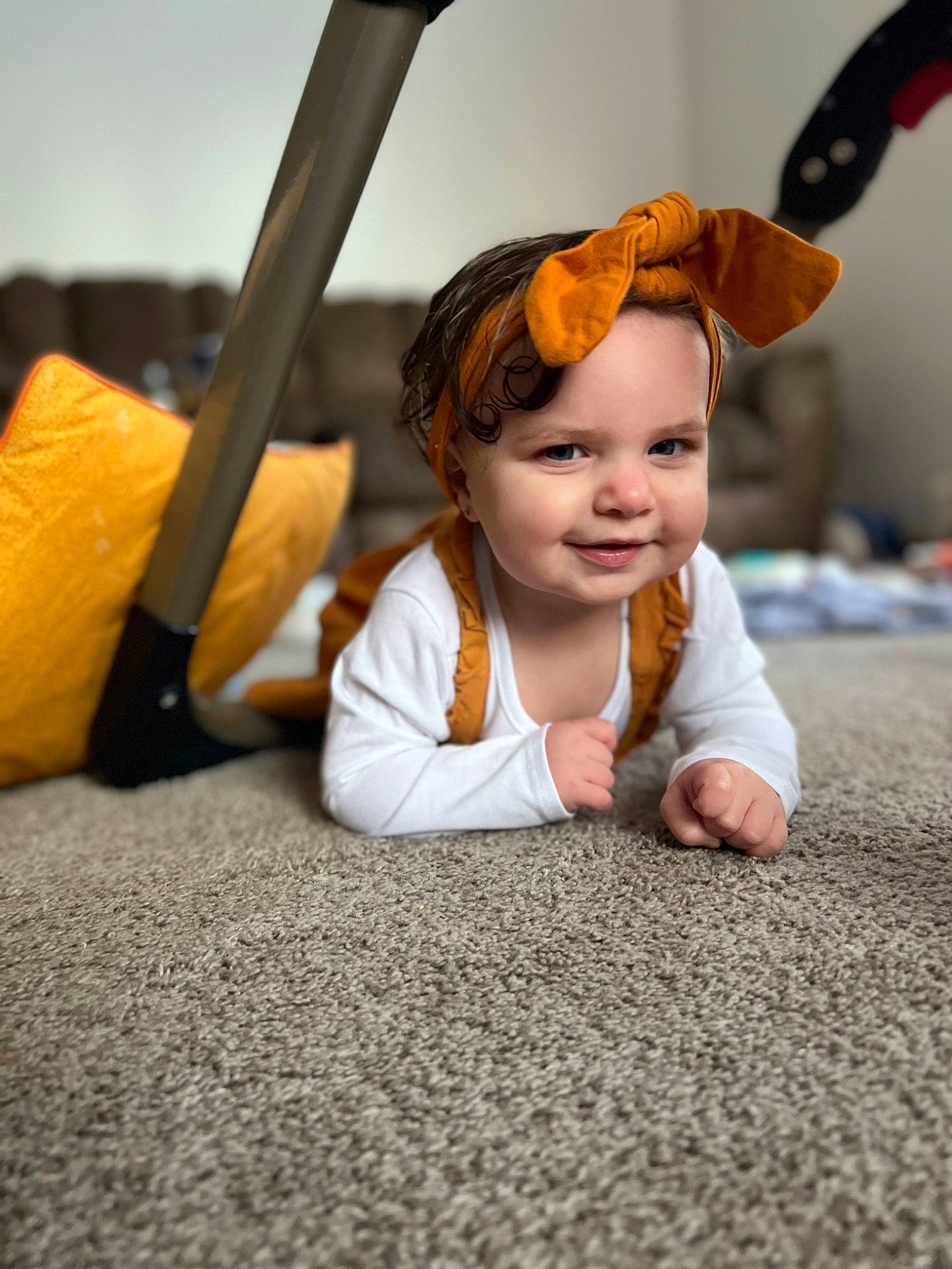 Bailey is registered to the contest to win money with this photo: asphalt, baby, baby_toddler_clothing, child, comfort, eye, face, floor, flooring, fun, happy, hardwood, head, joy, orange, person, road_surface, room, sitting, smile