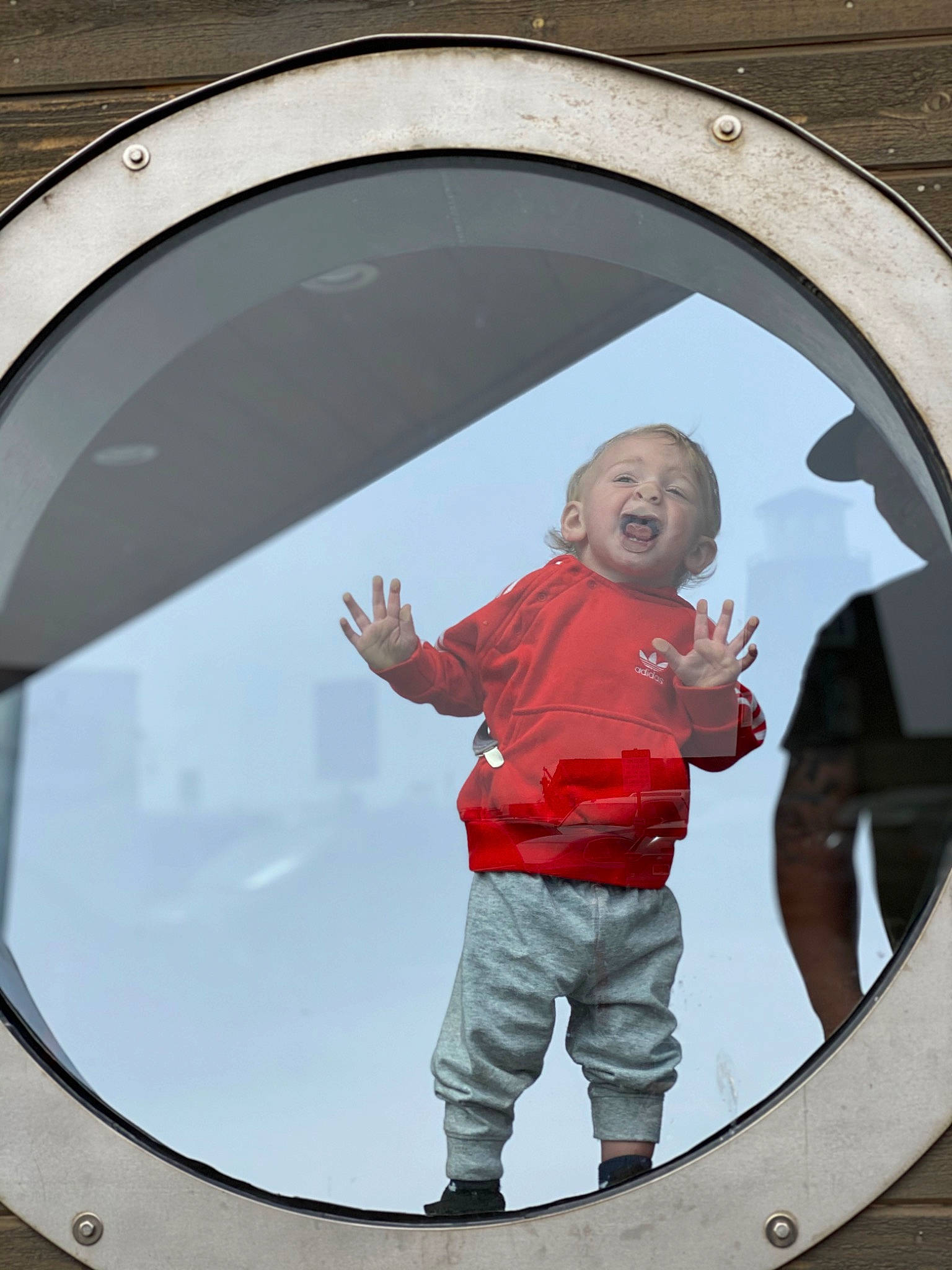 Brody is registered to the contest to win money with this photo: arch, auto_part, automotive_window_part, child, circle, daylighting, fixture, fun, gesture, glass, happy, person, photograph, reflection, sky, sleeve, smile, symmetry, t_shirt, toddler