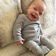 Alyanna a rejoint le concours — aidez-le/la à gagner de superbes lots ! baby, smiling, infant, knitwear, grey_clothing, blanket, soft_texture, happy, cute, portrait, child, person, cozy, sitting, indoors, young, skin, face, hand, comfort