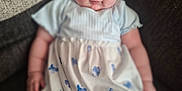 Edith is registered to the contest to win money with this photo: baby, blue_butterfly, casual, child, chubby_cheeks, comfortable, couch, curly_hair, cute, dress, expression, indoor, infant, person, portrait, relaxed, seated, soft_focus, white_dress, young_child