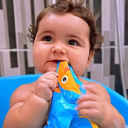 Ninon participe au concours pour gagner de l'argent avec cette photo : baby, child, curly_hair, blue_tub, toy, bathroom, chewing, cute, happy, infant, face, skin, hand, playful, water, indoor, smiling, young, closeup, portrait