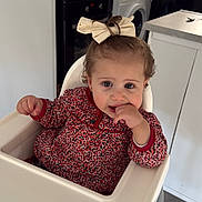 Elena participe au concours pour gagner de l'argent avec cette photo : toddler, child, high_chair, bow, finger_in_mouth, kitchen, washing_machine, fruit_bowl, corn_flakes_box, patterned_dress, curly_hair, indoor, appliance, countertop, sink, utensil, white_chair, floor, cabinet, cute