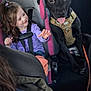 Max is registered to the contest to win money with this photo: child, dog, car_seat, harness, black_dog, happy, smiling, interior, vehicle, seat_belt, girl, pet, animal, young, cute, car, seat, leash, casual, toddler