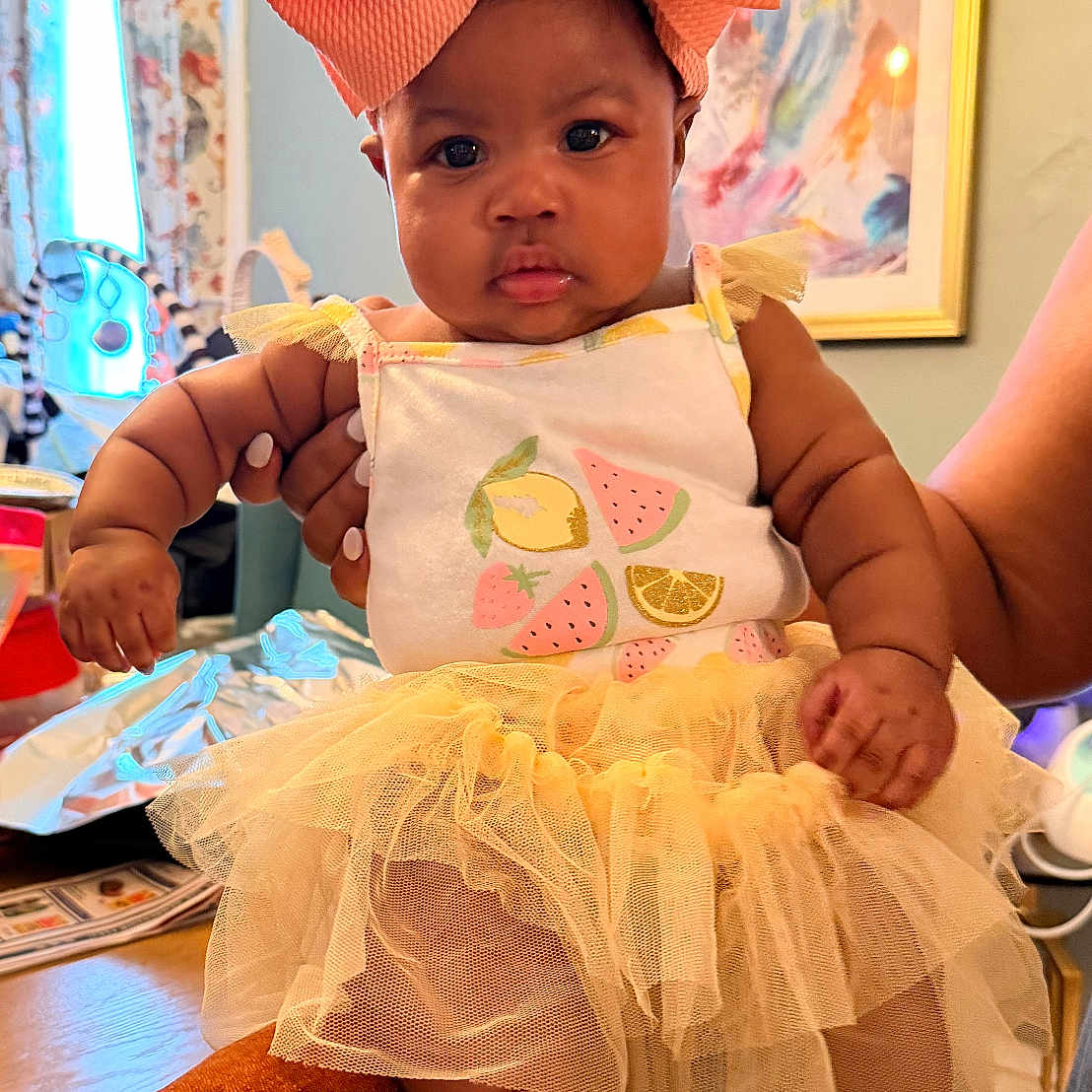 Ava-Rose joined the competition — help win amazing prizes! baby, infant, child, tutu, dress, bow, orange_bow, yellow_tutu, indoor, person, curtains, artwork, table, chair, hand, foot, face, cute, expression, holding