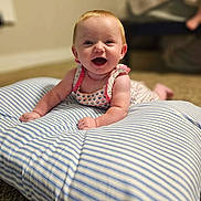 Emberly joined the competition — help win amazing prizes! baby, child, infant, smiling, happy, sitting, portrait, indoors, cushion, pillow, striped, blue_and_white, dress, floral, carpet, furniture, living_room, background, warm_lighting, face